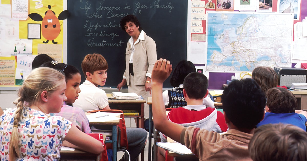 A teacher writing at a desk, representing a recommender drafting a letter of recommendation for a college applicant