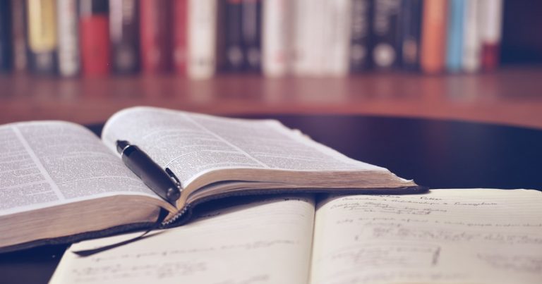 Student preparing for the SAT Reading and Writing section with notes and textbooks on a desk