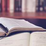Student studying for the enhanced ACT English and Reading sections with notes and a book