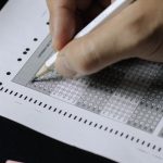 Student filling in a standardized-test answer sheet with a pencil, illustrating ACT test day preparation