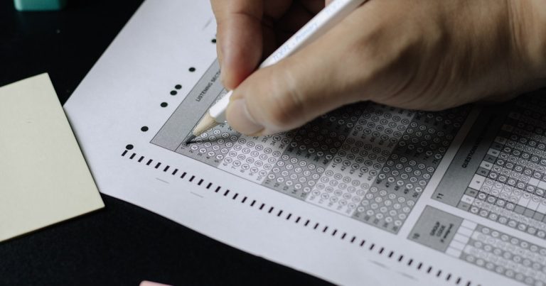 Student filling in a standardized-test answer sheet with a pencil, illustrating ACT test day preparation