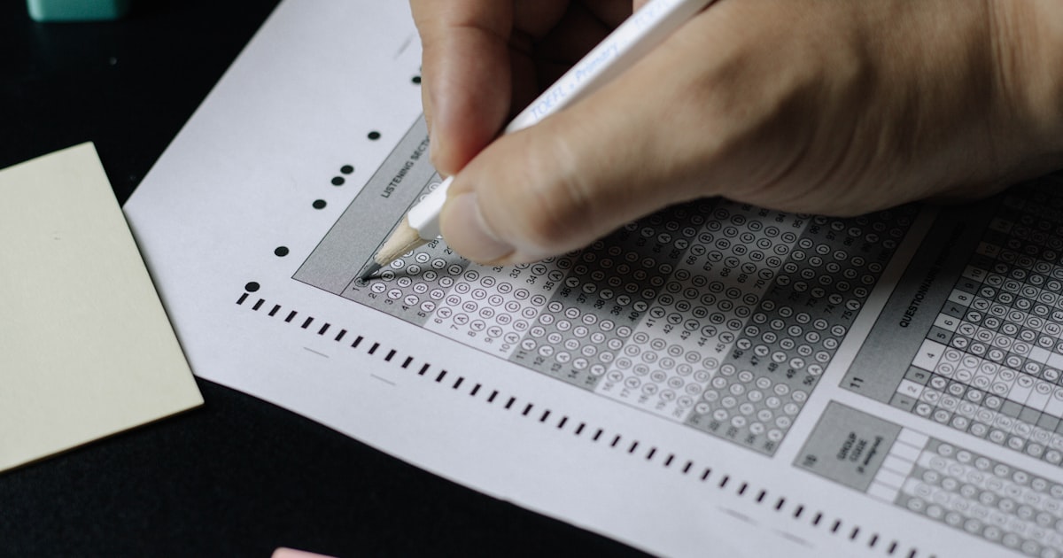 Student filling in a standardized-test answer sheet with a pencil, illustrating ACT test day preparation