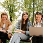 Three students sitting together reviewing college decision timeline and early application strategy