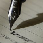 Student drafting a college personal statement essay by hand in a notebook