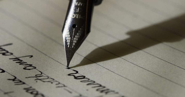Student drafting a college personal statement essay by hand in a notebook