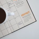 A wall calendar and notebook on a desk, marking application deadlines for TOEFL and IELTS score reporting