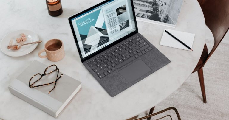 A laptop and wired headset on a clear home desk, illustrating the TOEFL Home Edition and IELTS Online at-home testing environment compared with a test center