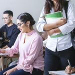 University students taking handwritten notes during a lecture, illustrating TOEFL Listening note-taking strategy